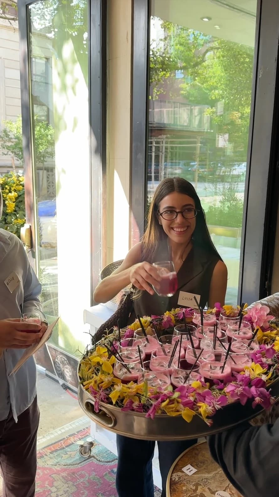 Guest taking a pink drink from a flower-covered tray at the launch event