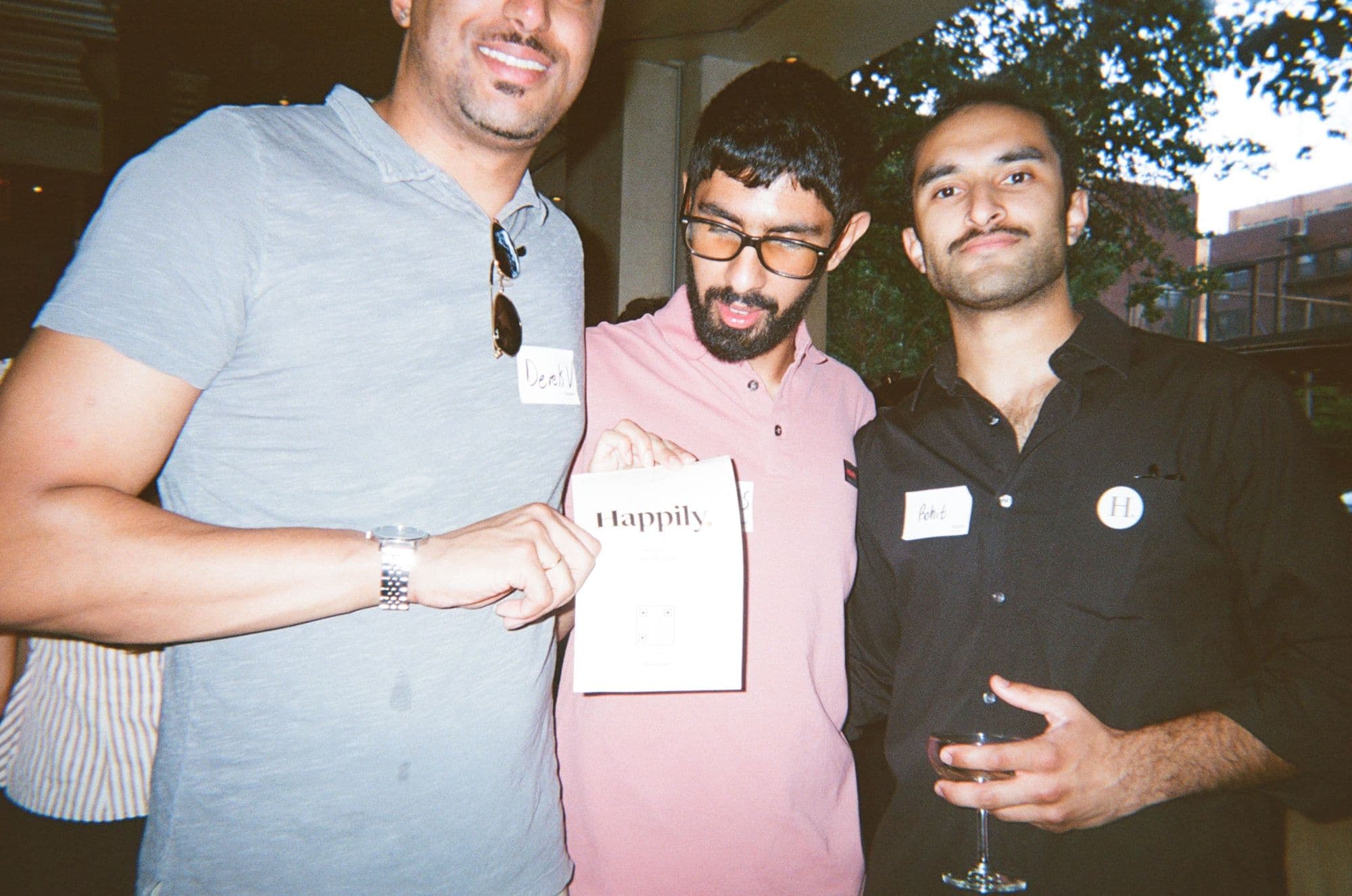 Three guests holding a Happily card at the launch event