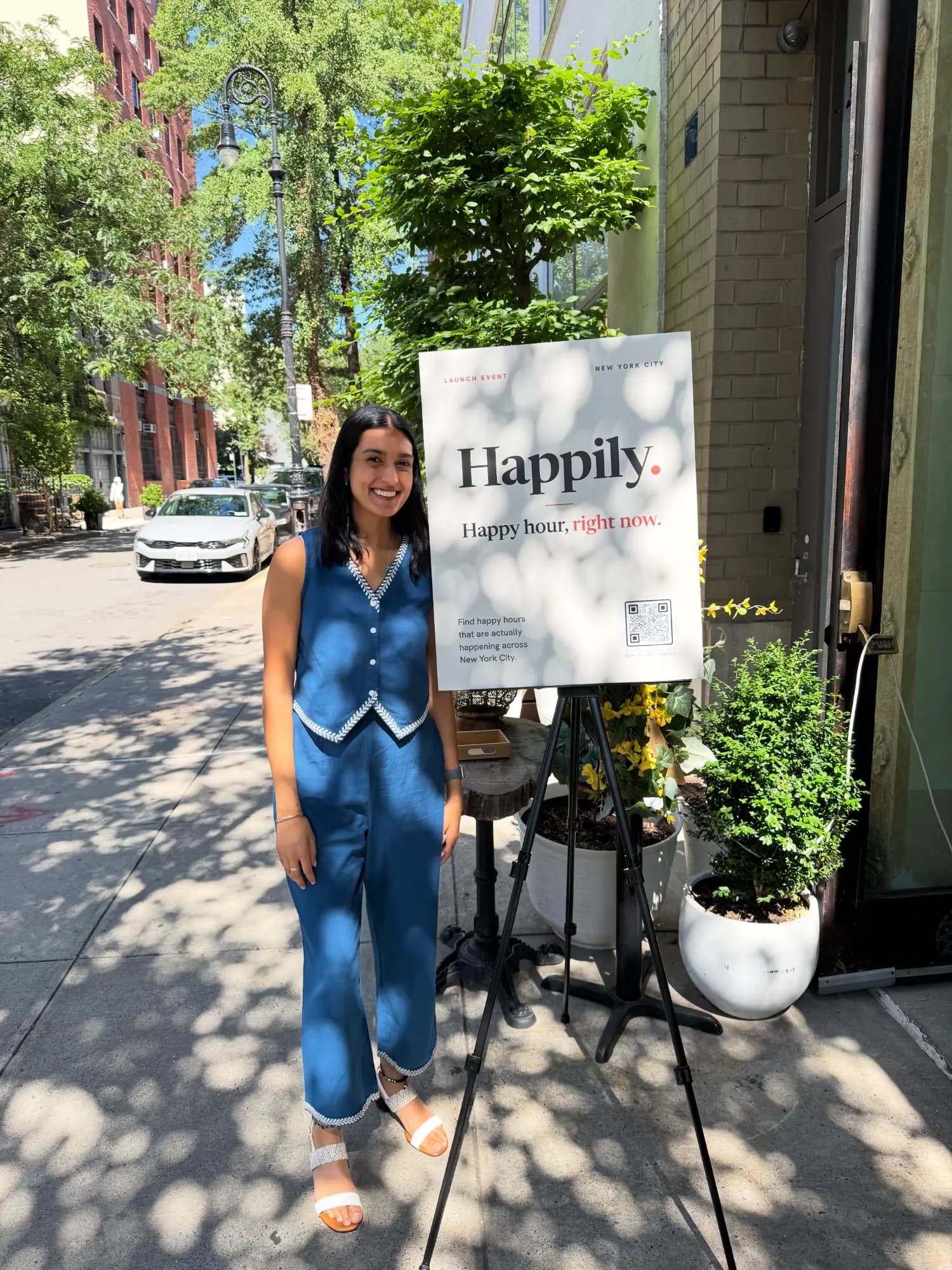 Guest smiling beside the Happily sign at the launch event